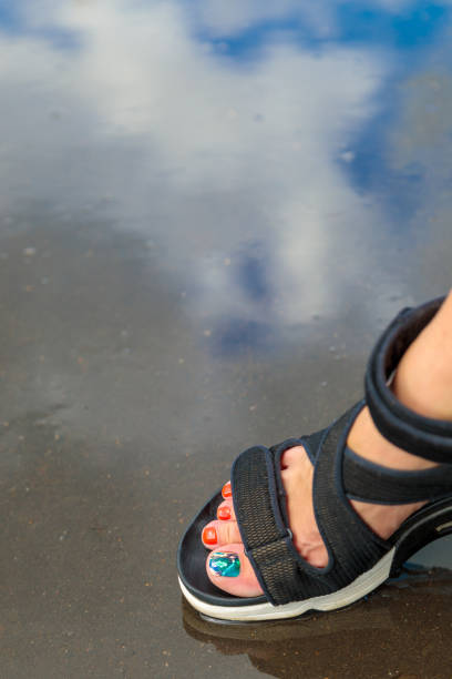 istock Foot in sandals on wet surface with reflection 2155533511