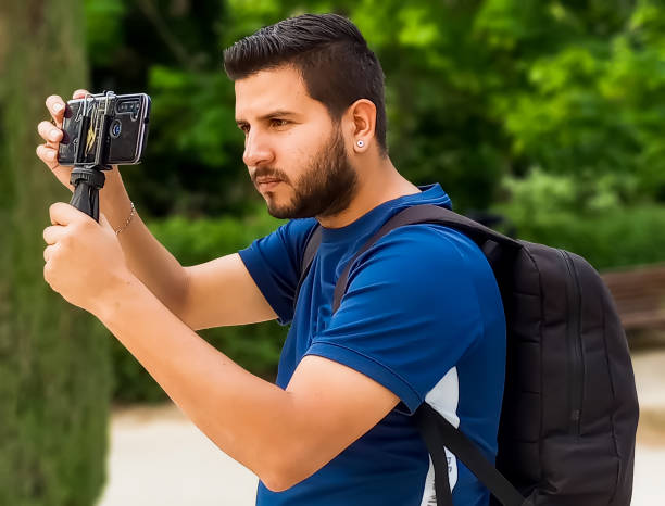 istock young latino photographer with cell phone in hand and black backpack 2155536428