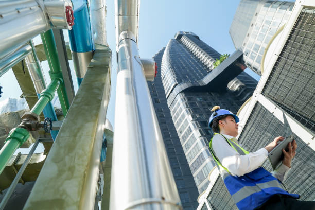 istock Industrial engineer adjusting pipeline valve with radio communication on construction site. Engineer on urban construction site using radio to coordinate with team on a sunny industrial rooftop. 2155536997