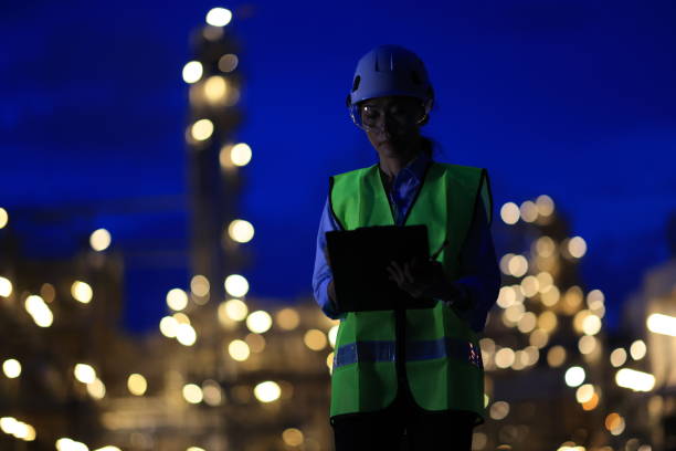 istock Female Industrial Engineer wearing safety vest and hardhat using digital tablet working at nightshift 2155546012