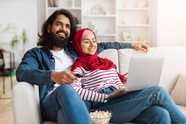 istock Man and Woman Sitting on a Couch With a Laptop 2155546397