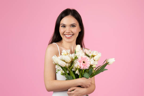 istock Lady embracing a fresh flower bouquet on pink background 2155546728
