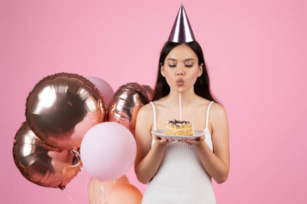 istock Lady blowing out a candle on a birthday cake 2155546744