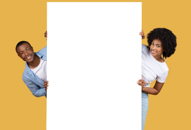 istock Couple peeking out from behind blank white banner 2155546947
