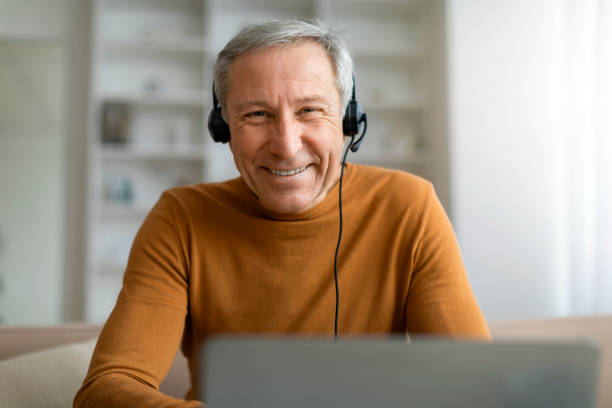 istock Closeup of old man using headset and laptop at home 2155547410
