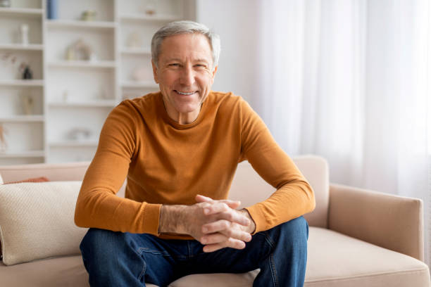 istock Positive senior man sitting on couch at home 2155547415