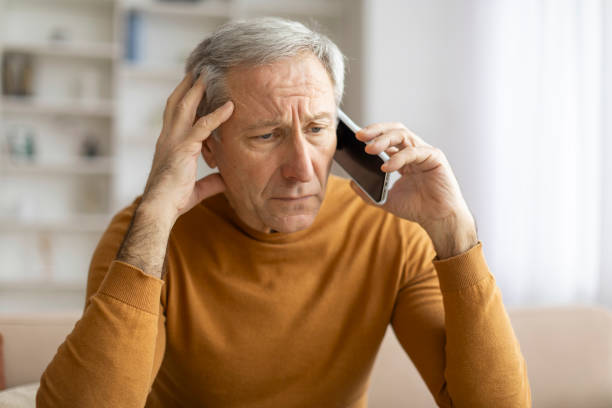 Senior man with concerned look holding phone
