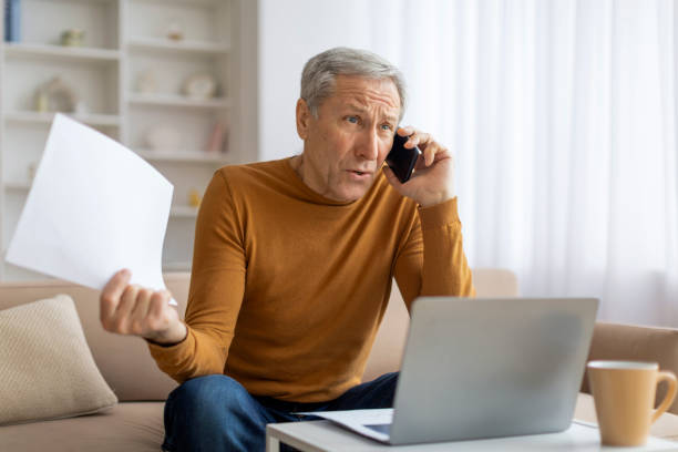 istock Man multitasking with phone, laptop, and papers 2155547488