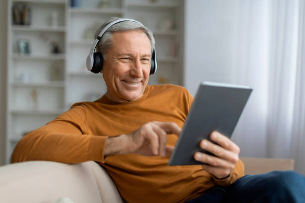istock Positive elderly european man using headphones and digital pad 2155547576