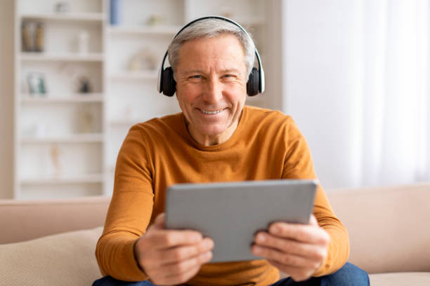 istock Happy elderly man using digital tablet and headphones at home 2155547582