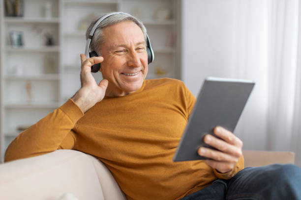 istock Happy senior man with headphones using tablet 2155547633