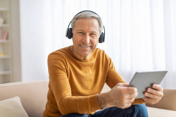 istock Smiling senior man with tablet and headphones 2155547641