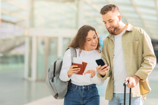 Couple reviews plans on smartphone at terminal