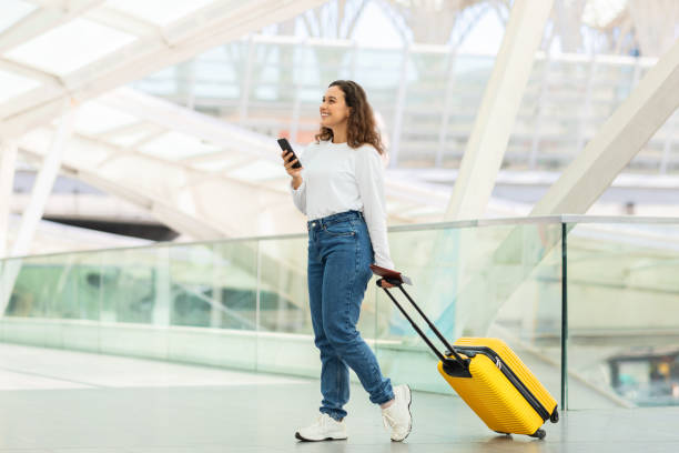 istock Woman using phone with luggage in tow 2155547800