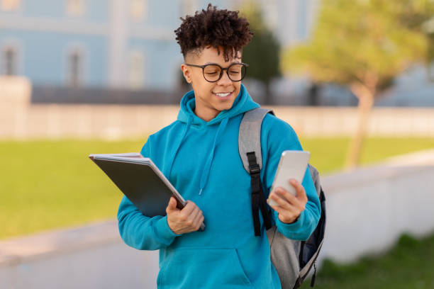 istock Walking student reading tablet and holding phone 2155547848