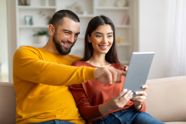 istock Happy Young Couple Using Digital Tablet While Relaxing At Home Together 2155547937
