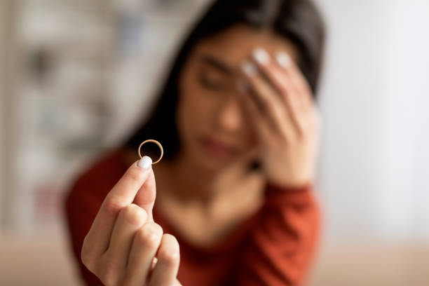istock Upset young woman holding wedding ring in focus with pained expression 2155548040