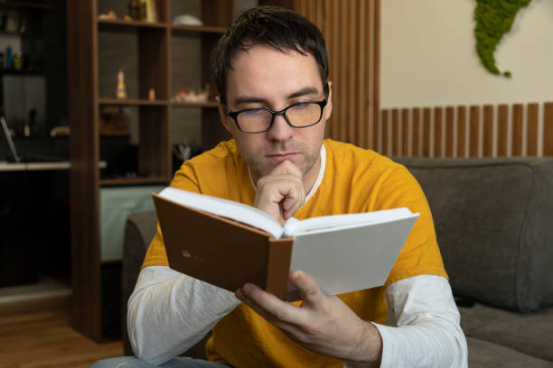 istock Young man sitting, reading a book and enjoying his leisure time 2155551857