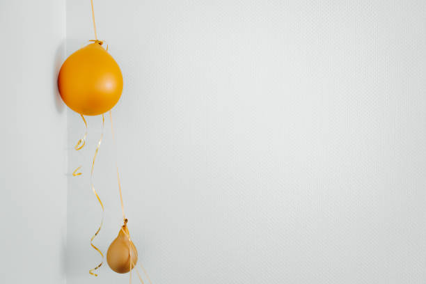 Deflated yellow balloons on golden string white background. After party holiday concept