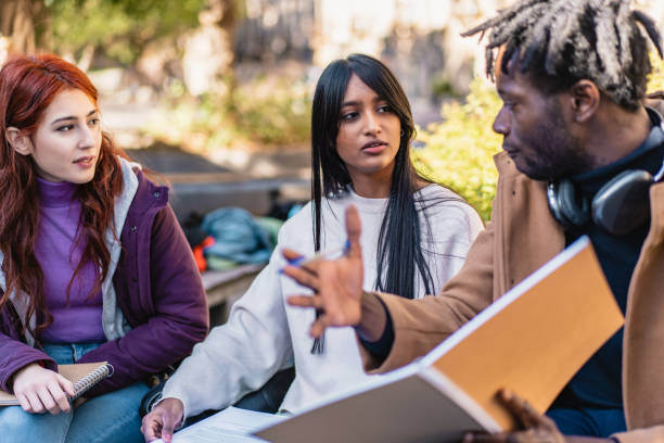 istock Three students engage in a lively discussion with notebooks and papers on a sunny campus day. A sense of collaboration and diversity is evident 2155554202