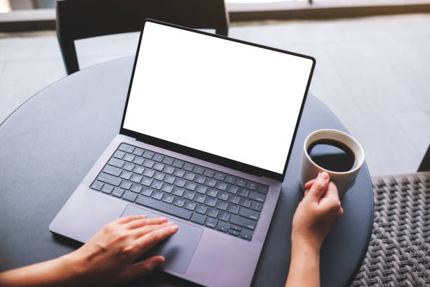 istock Top view mockup image of a woman working on laptop computer with blank white desktop screen while drinking coffee in cafe 2155555789