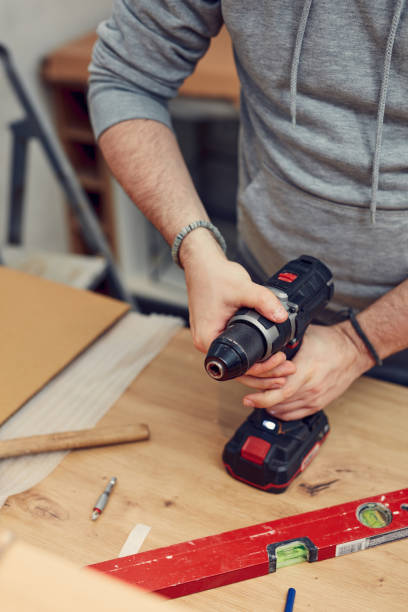 istock Handyman with battery drill and spirit level fixing kitchen cabinets. 2155555890