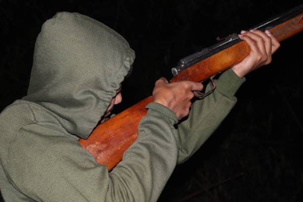 A man in camouflage is holding a shotgun. The image has a mood of adventure and excitement, as the man is likely preparing to hunt or engage in some outdoor activity
