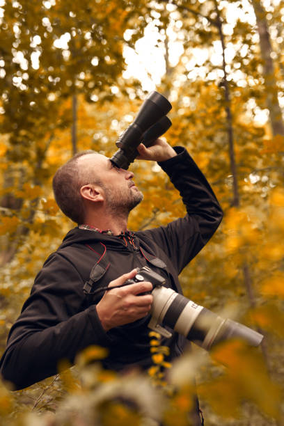 istock Man using binoculars and camera for birdwatching and other observing animals in nature. 2155557026