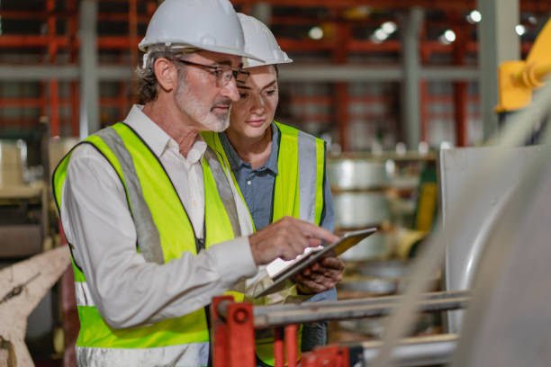 istock Industrial engineer team standing in manufacturing facility talking machinery maintenance in heavy industry 2155558945