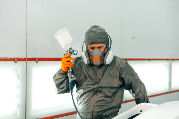 istock Auto mechanic worker wearing protective workwear spraying white paint on car part at workshop 2155559177