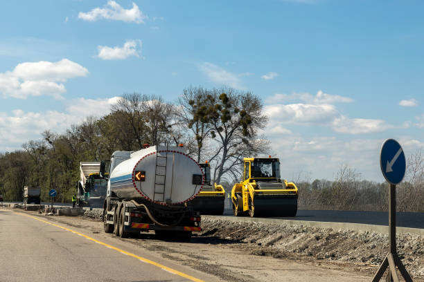 Highway intercity new road construction site with many heavy machinery steamroller, water tanker truck and paver tractor. Paving motorway road street works. Urban infrastructure development industry Highway intercity new road construction site with many heavy machinery steamroller, water tanker truck and paver tractor. Paving motorway road street works. Urban infrastructure development industry. flattening stock pictures, royalty-free photos & images