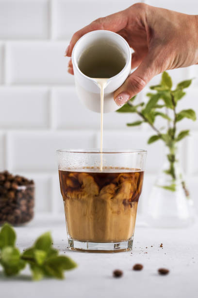 Refreshing glass of black coffee with a light foam, set against a modern white kitchen background