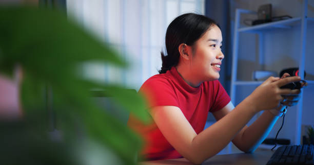 istock Young woman holding a joystick controller feels excited while having fun playing video games in the living room at home. 2155564930