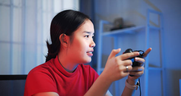 istock Young woman holding a joystick controller feels excited while having fun playing video games in the living room at home. 2155564948