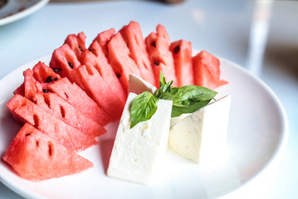 A white plate showcases slices of juicy watermelon and creamy cheese.