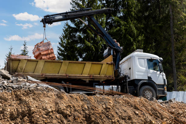 istock Side bottom pov big modern truck with mounted self loading crane arm boom unloading pallet of new bricks at countryside rural forest suburban construction site. Building materials delivery service 2155568719
