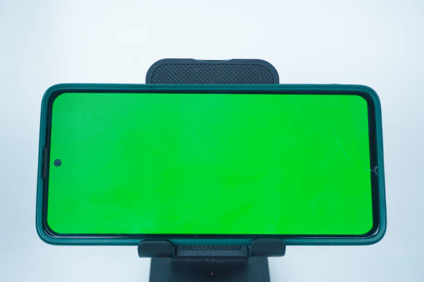 istock Phone with hole punch placed in stand showing green screen 2155569427