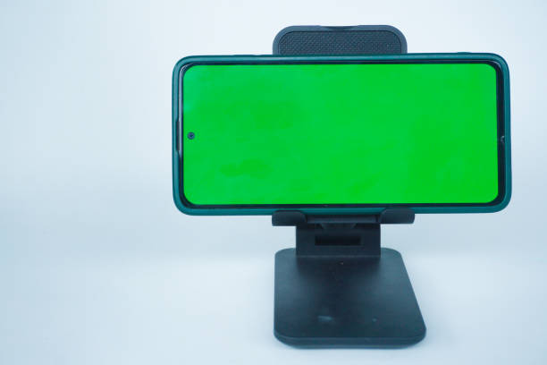 istock Phone with hole punch placed in stand showing green screen 2155569527