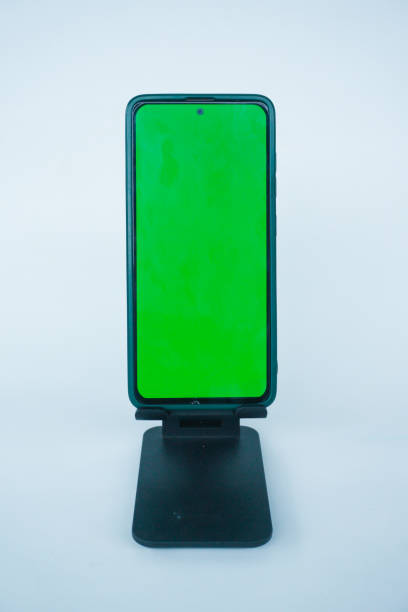istock Phone with hole punch placed in stand showing green screen 2155569578