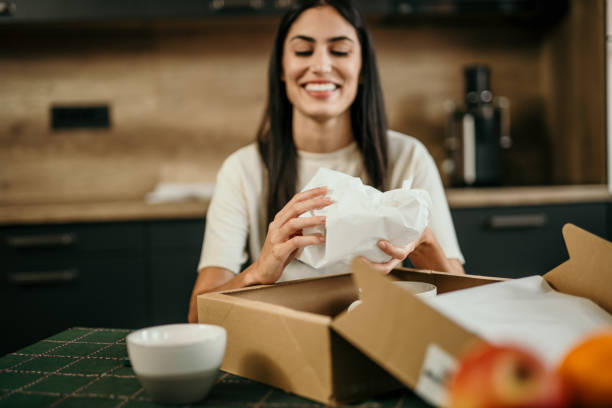 istock Joyful Hispanic lady unwrapping a package in her cozy home 2155574482