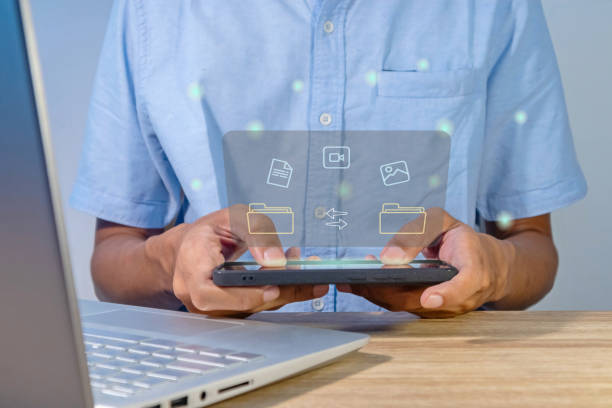 istock File transfer between mobile phone and laptop. Copy file and media or exchange data on virtual screen. 2155579843
