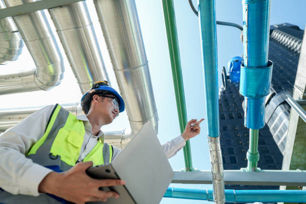 istock Industrial engineer adjusting pipeline valve with radio communication on construction site. Engineer on urban construction site using radio to coordinate with team on a sunny industrial rooftop. 2155583885