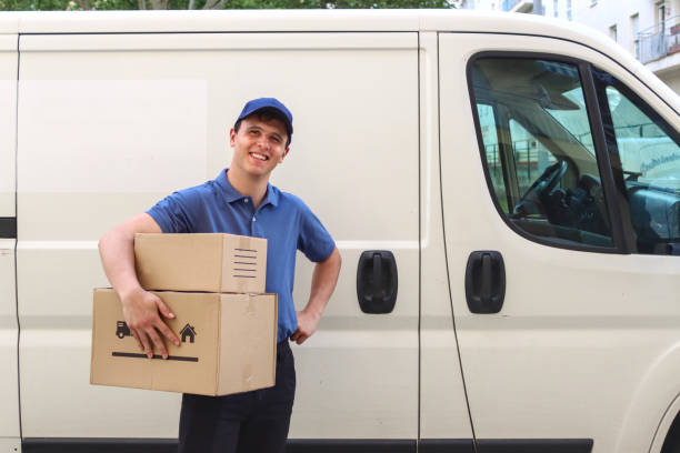 istock Portrait of package delivery man smiling next to a van 2155586817