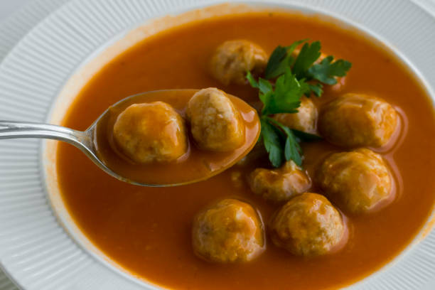 Above view of Traditional Turkish Meatball Soup,holding two ball with spoon.