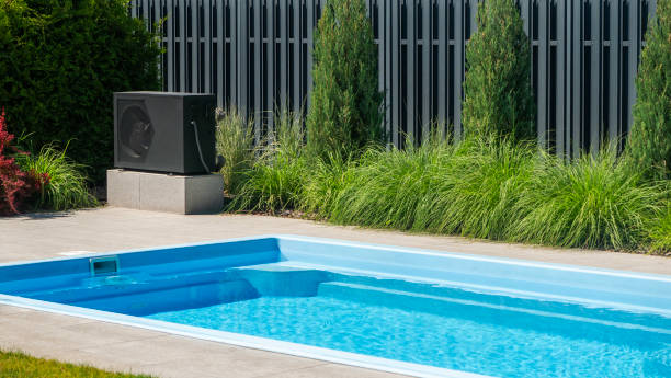 istock Heat pump unit beside a swimming pool with decorative greenery. 2155589694
