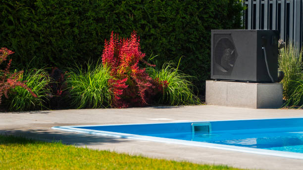 istock Heat pump unit beside a swimming pool with decorative greenery. 2155590331