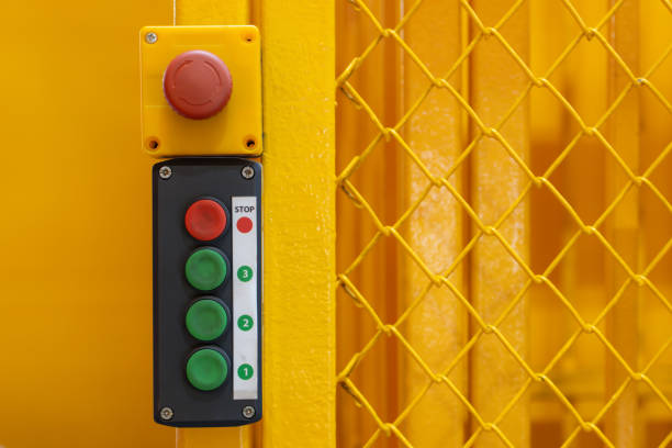 A yellow metal gate with a red button on it