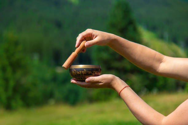 A woman holds a singing bowl in her hands. Selective focus.