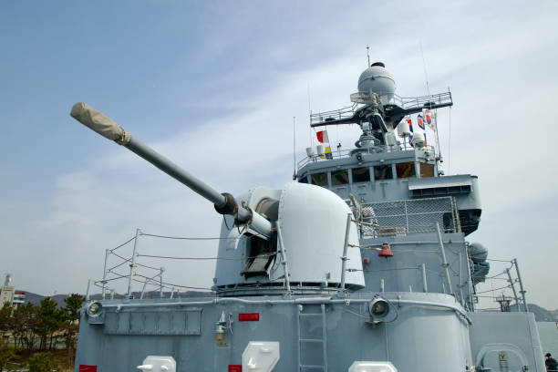 Ulsan, South Korea - March 17th, 2024: An artillery gun is prominently displayed on the deck of the Ulsan Frigate at the Jangsaengpo Whale Museum, with the bridge and radio tower visible in the background, showcasing the vessel's formidable defense capabilities.