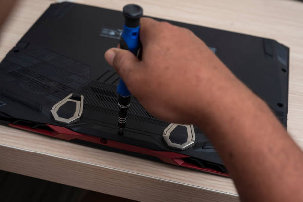 istock A computer technician removes the bottom cover panel of a laptop with a screwdriver. Laptop maintenance and cleaning. 2155598953